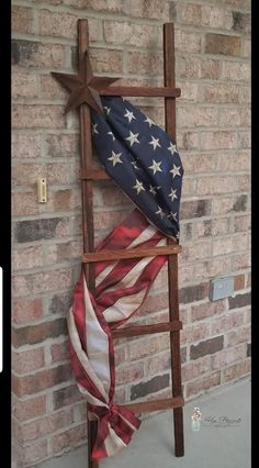 an american flag on a wooden ladder next to a brick wall