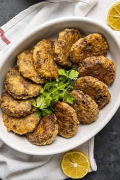 a white bowl filled with fried meat and garnished with cilantro leaves