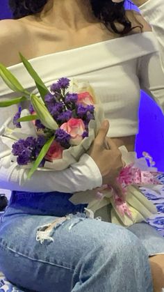 a woman sitting down holding a bouquet of flowers