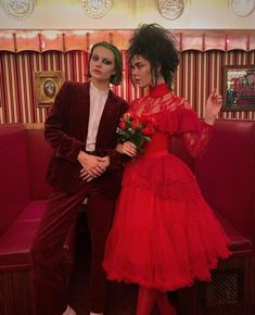 a man and woman dressed in red posing for the camera with one holding a flower