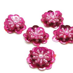 four pink flowers with pearls on them sitting next to each other in front of a white background