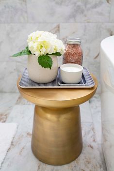 a gold pedestal with a white flower and salt shaker sitting on top of it