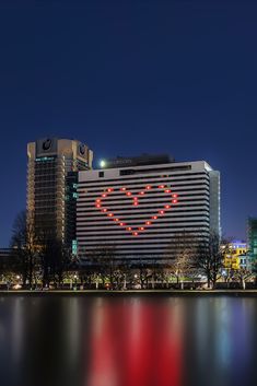 a large white building with a heart on it's side next to the water