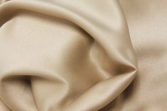 a close up view of a plain beige fabric with very soft folds and wrinkles