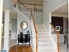 a staircase leading up to a living room with a mirror on the wall above it