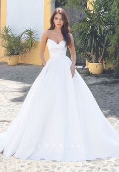 a woman in a white wedding dress posing for the camera with her hands on her hips