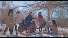 four girls are standing in the snow with their horses and one girl is holding her hand out