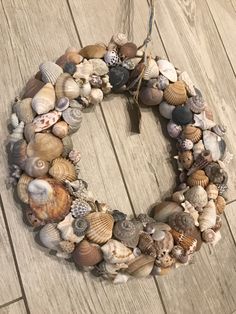 a wreath made out of seashells on a wooden floor with a string attached to it