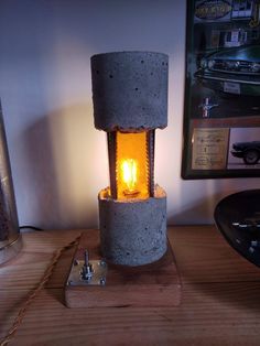 a concrete lamp sitting on top of a wooden table next to a metal canister