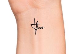 a small cross tattoo on the wrist that says,'love'in cursive font