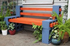 an orange and blue bench sitting next to some potted plants