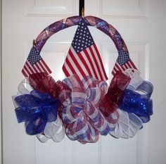 a patriotic wreath hanging on the front door with an american flag and red white and blue bow