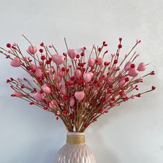 a white vase filled with pink flowers and red berries on top of it's side