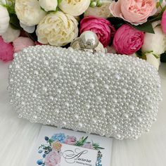 This luxurious encrusted pearl bridal clutch never fails to turn heads with its understated elegance and classic design. Adorned with varying sized ivory pearls and enhanced with a large creamy pearl clasp, this bridal clutch is the very picture of refinement. This elegant bridal clutch features rose gold trim, attachable chain and large enough for your phone. Complete your list of must-have wedding accessories with the ultimate bridal accessory to finish off your look and storing your wedding d Silver Clutch With Pearl Embroidery For Party, Silver Party Evening Bag With Pearl Embroidery, Silver Evening Bag With Pearl Embroidery For Party, Silver Pearl Embroidery Evening Bag For Party, Handheld Beaded Evening Bag For Wedding, Wedding Bag With Pearl Handle In Silver, Rectangular Beaded Evening Bag For Wedding, Pearl White Clutch For Wedding, Silver Evening Bag With Pearl Handle For Wedding