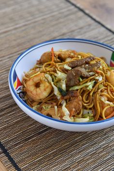 a bowl filled with noodles and meat on top of a table