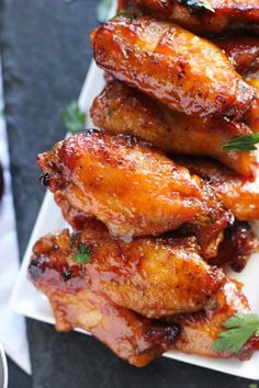 some chicken wings are piled on top of each other with garnish and parsley