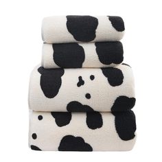 three black and white cow print towels stacked on top of each other in front of a white background