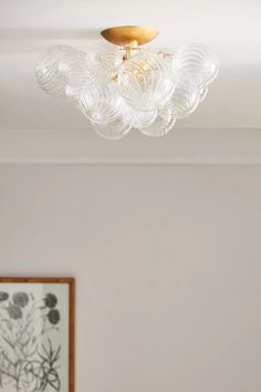 a chandelier hanging from the ceiling in a room with white walls and paintings