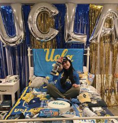 a woman sitting on top of a bed surrounded by balloons and confetti in the shape of letters