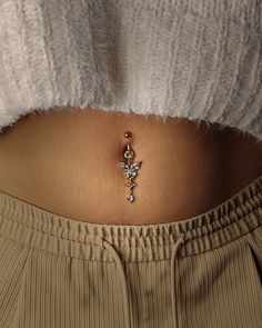 a woman's belly is adorned with a gold cross and diamond brooch pin