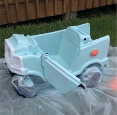 a plastic toy truck sitting on top of a tarp in the grass next to a fence