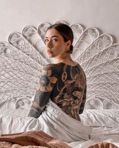 a woman sitting on top of a bed covered in tattoos