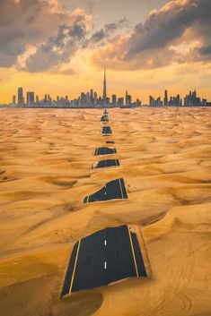 an aerial view of a highway in the middle of desert with skyscrapers in the background