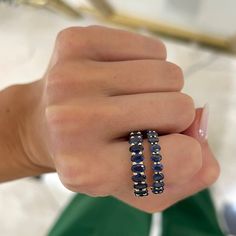 a woman's hand holding two rings with blue beads on each ring and the other beaded in gold