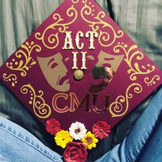 a red cap with the words act ii cnu written on it and flowers in front of it