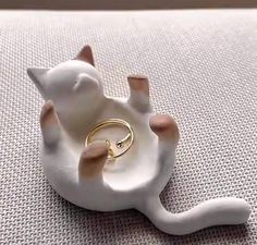 a white cat figurine with a ring on it's back