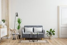 a living room with white walls and wooden flooring is furnished with grey couches