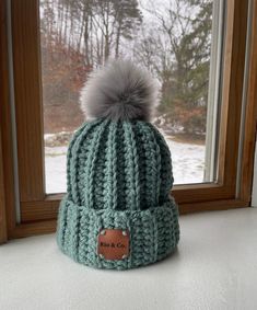 "Keep warm in this chunky hand crocheted fold over hat Button inside to remove Pompom  20% wool 80% acrylic Height: 8.5\" (measurement does not include Pompom) Circumference: 20\" Hand wash hat only  Lay flat to dry  *Color may look slightly different depending on viewing screen" Cozy Green Hat For Fall, Cozy Green Fall Hats, Green Crochet Beanie For Winter, Green Winter Crochet Beanie Hat, Handmade Green Crochet Hat For Winter, Green Crochet Hat For Winter, Green Yarn Crochet Hat For Outdoor, Green Fitted Crochet Hat For Winter, Fitted Green Beanie For Winter