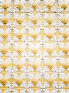 white and yellow flowers are arranged on a tile wall in the shape of a flower