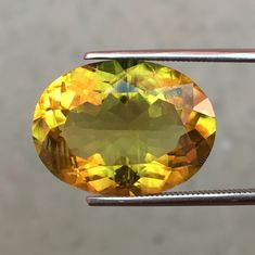 an oval shaped yellow diamond being held by a pair of tongs