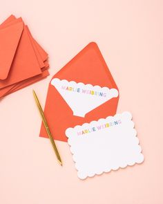 an envelope, notepad and pen on a pink surface