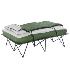 a green and white bed sitting on top of a metal frame with two sheets folded over it