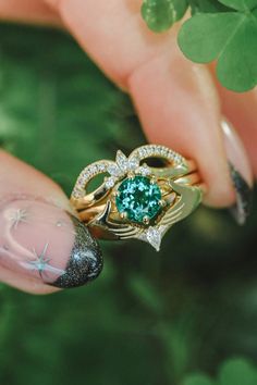 a woman's hand holding a ring with a green stone in the middle and stars on it