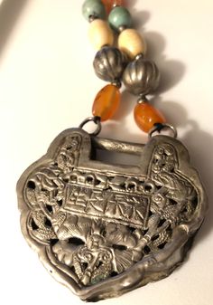 "Created originally as a \"wedding lock\", this 100 year old Oriental piece was put on a necklace of a young daughter until she was married, when it was \"unlocked\" and saved to be handed down to her daughters. Dating to 1900-1910s, the piece has a handmade silver reposse double sided lock pendant. It's on a beautiful woven silver chain that also has carnelian and turquoise and silver beads. The chain is approximately 32 inch total not including the lock, which measures nearly 2 1/2\" by 2 1/4\ Antique Amber Jewelry With Polished Beads, Antique Jewelry With Round Beads For Vintage Collection, Traditional Jewelry With Natural Stones For Collectors, Traditional Silver Carnelian Necklace, Antique Beaded Pendant Necklace, Traditional Medallion Necklace For Collectors, Traditional Medallion Necklace From Vintage Collection, Vintage Pendant Necklaces With Polished Beads, Vintage Pendant Necklace With Polished Beads