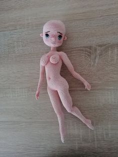 a pink crocheted doll laying on top of a wooden floor next to a wall