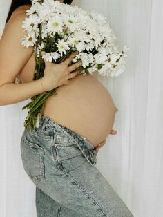 a pregnant woman holding flowers in her belly