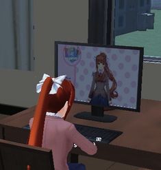 a person sitting at a desk in front of a computer monitor with an animated character on the screen