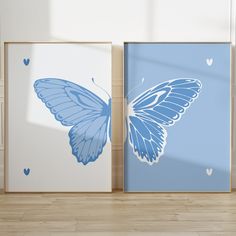 two blue and white butterfly prints on the wall next to each other in a room