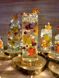 lighted glass vases with autumn leaves and berries in them on wood slices, surrounded by fairy lights