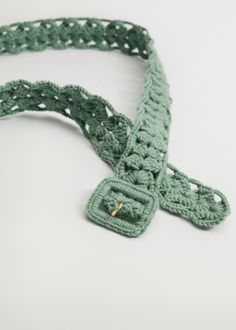 a green crocheted belt with metal buckles