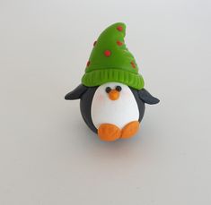 a penguin with a green hat on top of it's head, sitting next to a white background