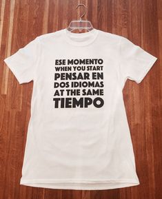 "- Amusing T shirt with the slogan \"Ese Momento When You Start Pensar En Dos Idiomas At The Same Tiempo\". Great for Spanish language students o estudiantes de Ingles! - Available in sizes S up to XL. - 100% ringspun cotton with a slimmer 'Euro Fit' which gives it a tailored effect. - Wash Instructions - Wash at 30 degrees inside out, do not bleach, do not tumble dry. Cool iron on reverse side of the garment. Never iron over the print." Funny Quote Print White T-shirt, Funny White T-shirt With Quote Print, Mexican T Shirts, Spanish Shirts, Funny Kids Shirts, Student Humor, Spanish English, Tshirt Bag, The Office Shirts