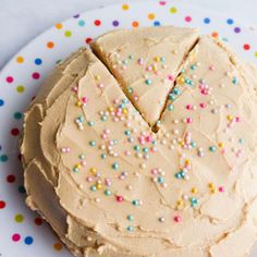 a cake on a plate with sprinkles and frosting cut into pieces