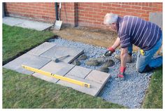 a man is working with cement in front of a brick wall and green grass on the ground