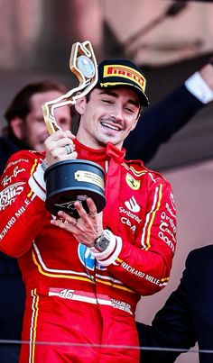 a man in red racing suit holding up a trophy