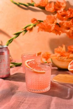 two glasses filled with pink lemonade sitting on top of a table next to flowers